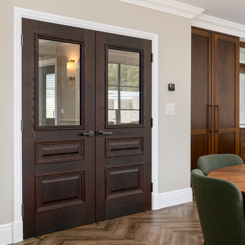 Wooden double doors with glass panels in a room with a table and chairs.